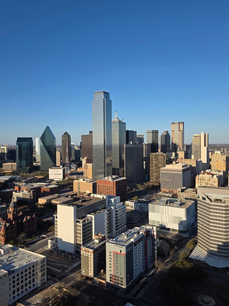 Aerial view of Dallas skyline featuring modern skyscrapers against a clear blue sky.